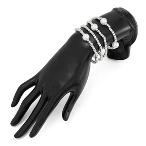 Detail of four-piece layered bracelet set with silver beads and white pearls on black hand