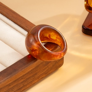 Macro detail of amber resin ring featuring vintage marble texture on wooden stand