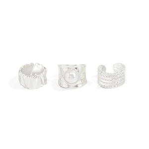 Detailed view of silver rings set with white pearl and hammered texture details