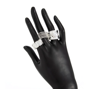 Detailed view of three silver rings set including twisted bands and a white pearl ring