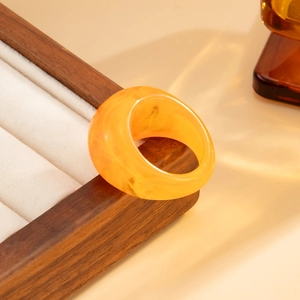 Close-up of amber resin wide ring with marble texture on a wooden jewelry box