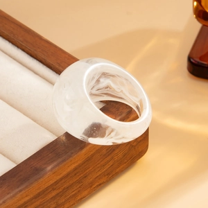 Detail of marble pattern resin ring on premium wooden display tray with soft lighting