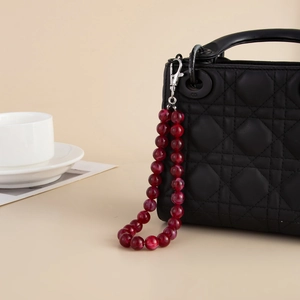 Red marble acrylic bead bag chain with silver lobster clasp on a quilted leather bag