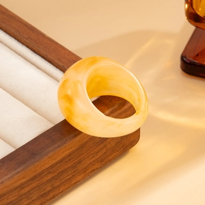 Detailed view of yellow marbled resin ring on premium display case for stacked wear