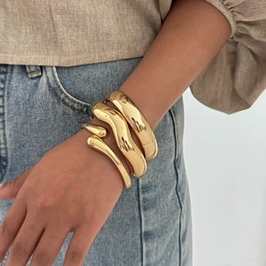 Three-piece stackable gold metal cuff bracelets featuring polished geometric surfaces
