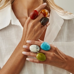 Close-up of colorful resin rings in brown, blue and marble tones on a model's hand