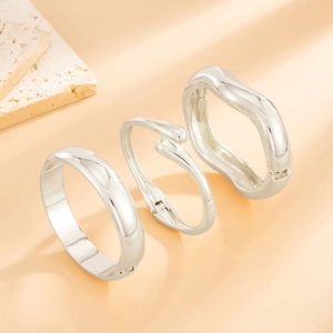 Detailed close-up of three silver-tone geometric bracelets with a high-polished mirror finish