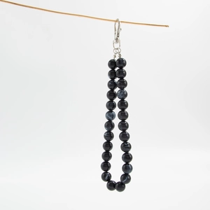 Detail of glossy black acrylic beaded strap with silver metal lobster clasp for bags