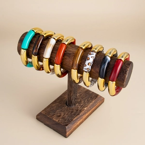 Detalle de pulseras de resina colorida tipo bambú en un soporte de exhibición de madera
