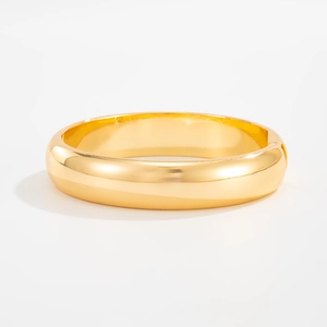 Macro detail of golden teardrop open bangle with polished surface and hinge closure
