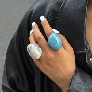Close-up of artistic marble and ocean blue resin rings worn with a black leather jacket
