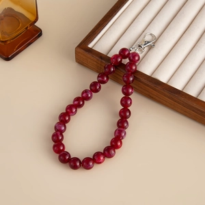 Detail of red marble acrylic beaded charm with silver metal clasp on a wooden box