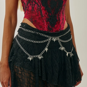 Detail of silver multi-layer waist chain with gothic bat pendants on black lace skirt
