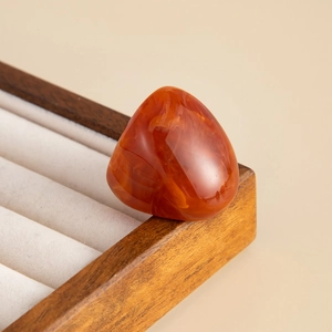 Macro view of amber resin ring with textured orange flow pattern on display stand