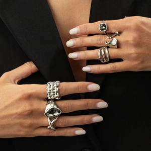 Détails de bagues vintage en argent avec pierres noires sur une main et veste noire