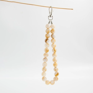 Detail of beaded bag chain with creamy marbled resin beads and silver lobster clasp