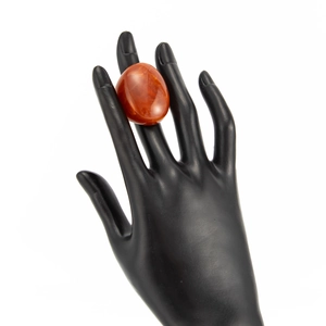 Close-up of translucent reddish-orange resin ring on a black hand mold