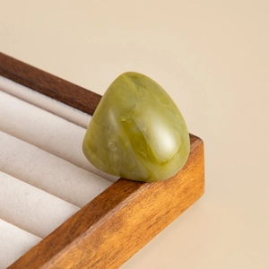 Detail of green resin ring with marble texture resting on a wooden jewelry display