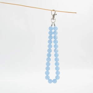 Macro shot of 26 light blue translucent beads and silver lobster clasp on a bag charm