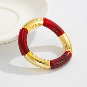 Detalle de pulsera elástica estilo bambú con tubos dorados y cuentas de resina marmoleada