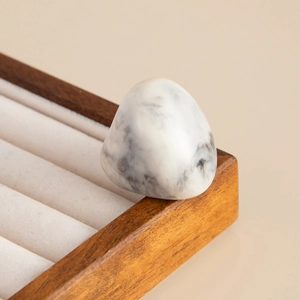 Macro detail of a resin ring with black and white marble texture on a velvet tray