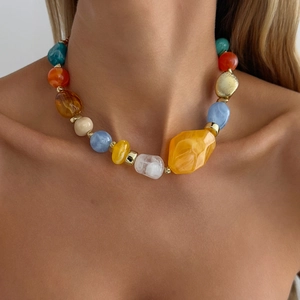Close-up of bohemian colorful resin beads and gold-tone CCB accents on a layered necklace