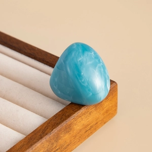 Close-up of blue resin ring with white marbling texture on a wooden jewelry tray