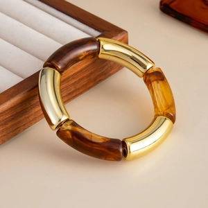 Primer plano de segmentos de resina de leopardo y metal dorado en la pulsera elástica