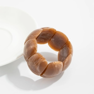 Close-up of amber resin stretch bracelet with marble texture on minimalist white background