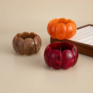 Macro detail of three resin bangles featuring marble patterns in brown orange and burgundy