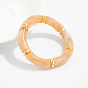 Detailed macro view of resin marble tube beads with gold metal dividers on an elastic bracelet