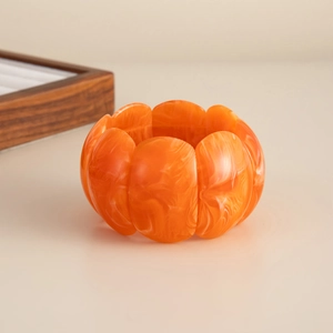 Macro detail of an orange resin elastic bracelet with white marble texture and wavy edges
