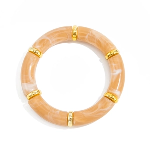 Detail of apricot marble resin tube bracelet with golden spacers on a clean white background