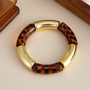 Detalle de pulsera elástica con segmentos de metal dorado y resina de carey estilo retro
