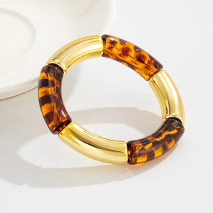 Detalle de segmentos de resina de carey y tubos metálicos dorados en pulsera elástica