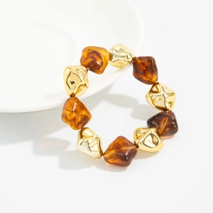 Close-up of amber resin beads and gold metal spacers on a wide elastic bracelet
