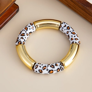 Detalle de pulsera de resina de leopardo y tubos metálicos dorados estilo bambú