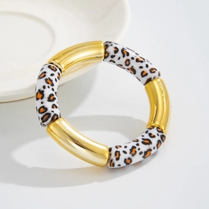 Detalle de pulsera elástica con resina de leopardo y tubos metálicos dorados en plato