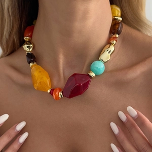 Close-up of bohemian chunky beaded necklace with colorful resin and golden irregular beads