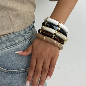 Detail of stacked acrylic tube bangles with marble patterns and gold metal spacers