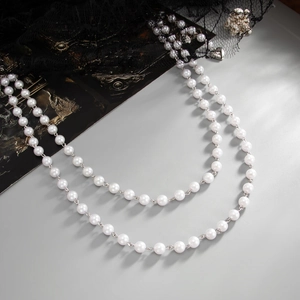 Détail de la chaîne de taille à double couche de perles et pendentif croix style gothique