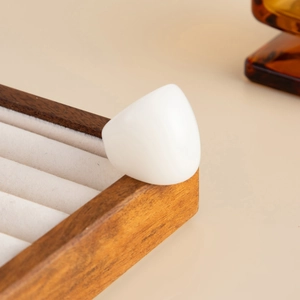 Close-up of minimalist wide white resin ring on a wooden tray with warm lighting