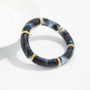 Detailed macro of acrylic bracelet sections with black ink marble texture and gold rings