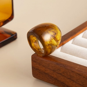 Detailed view of an amber resin ring with marble texture on a wooden jewelry box
