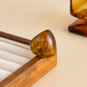 Macro shot of an amber resin chunky ring with marble texture on a vintage wood box