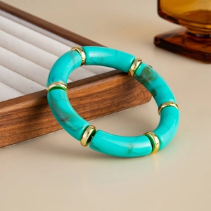 Detail of turquoise marble texture acrylic tube beads with golden spacers on a bracelet