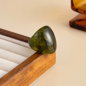 Macro detail of dark green resin ring with marble texture on velvet jewelry box