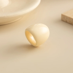 Detail of minimalist cream resin wide ring with smooth finish and tortoiseshell texture