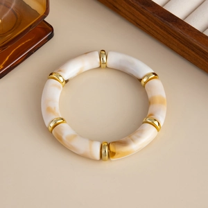 Detail eines Acryl-Segmentarmbands mit cremefarbenen Bernsteinperlen und Goldakzenten