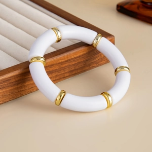 Close-up of bamboo-style elastic bracelet with white acrylic tubes and gold metal spacers